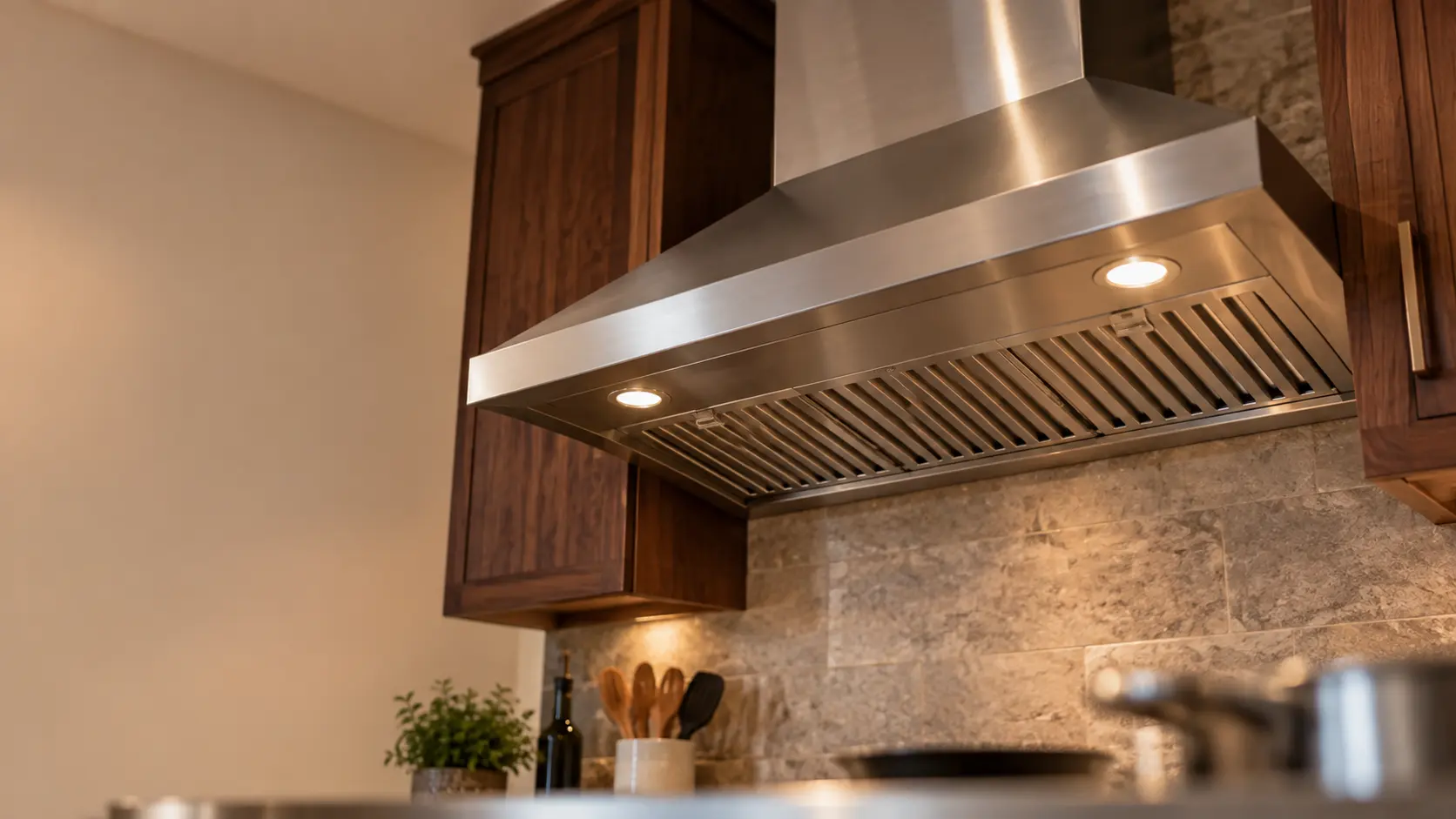 A kitchen with a stainless wall-mount range hood and dark walnut cabinets, seen from below the range hood.