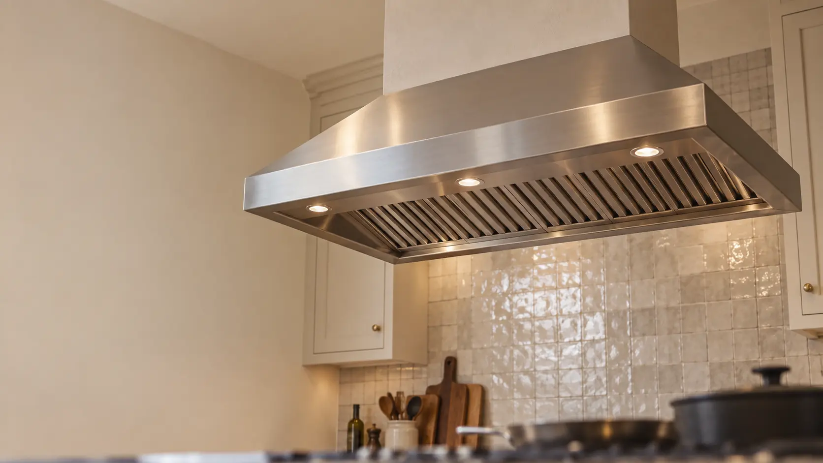 A kitchen island with an island range hood above it and a zellige tile backsplash, seen from below the range hood.