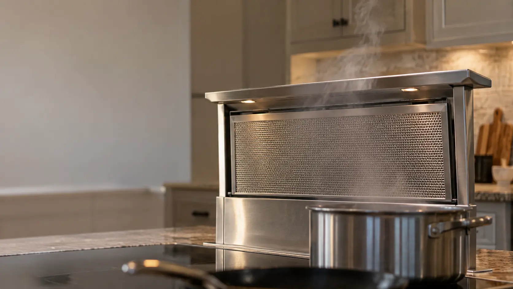 A stainless pop-up downdraft vent risen halfway behind the burners of a kitchen island, stalled at an angle, a thin wisp of steam from a pot passing over its top edge.
